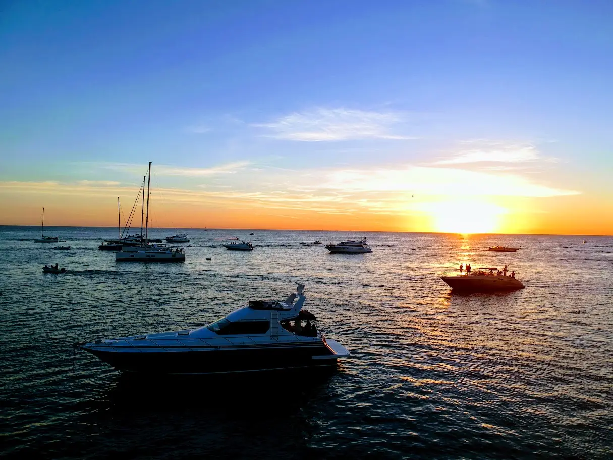 Yate navegando al atardecer entre otras embarcaciones frente a Punta del Este